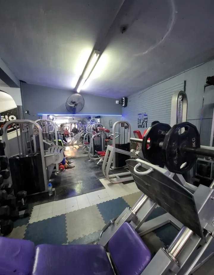 Zona de peso libre con mancuernas, discos y máquinas del Gimnasio Aquiles
